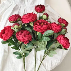 Vista dettagliata di peonie artificiali rosse su sfondo in tessuto bianco testurizzato