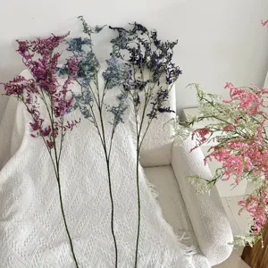 Detalle de flores de statice artificiales de varios colores sobre un sofá blanco