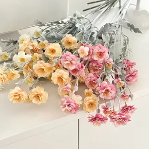 Detailed view of pink and peach flocked artificial camellia bouquet on white table