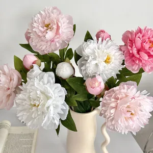 Close-up of artificial pink and white peonies in a unique cream wavy handle vase
