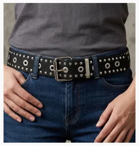 Detailed view of black punk style nylon belt with silver studs and eyelets on jeans