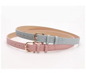 Detail view of woven texture and horseshoe gold buckle on pink and grey belts