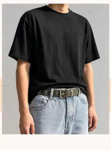 Detail view of an olive green punk rivet belt styled with denim jeans and black T-shirt.