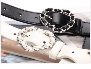 Close-up of elegant black and white women's belts with decorative chain-link buckles.