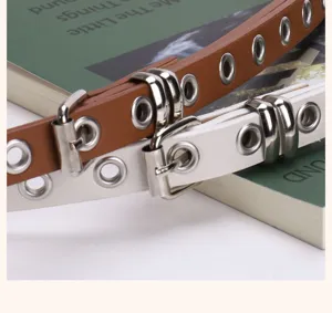 Close-up detail of vintage punk grommet belts in brown and white PU leather.