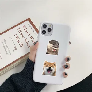 Vue détaillée d'autocollants drôles de loutre et de Shiba Inu sur une coque blanche