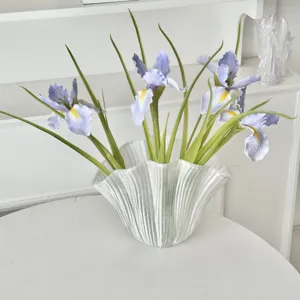 Detailed view of artificial purple iris flowers in a stylish textured glass vase