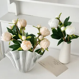 Detail of life-like champagne and white peony flowers in a decorative glass vase