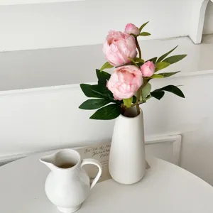 Detail of realistic pink 2-head silk peony simulation flowers in a minimalist white vase