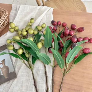 Detailed view of green and burgundy artificial fruit branches on rustic linen cloth