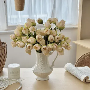 A bouquet of 24 cream-colored artificial tulips placed in an elegant white relief vase