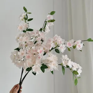 Detailed view of light pink artificial cherry blossom branches held by hand