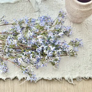 Μακροεντολή τεχνητών μπλε λουλουδιών σε σχήμα αστεριού σε κρεμ υφασμάτινο φόντο με υφή