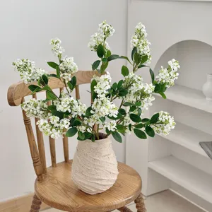 Detailed view of white artificial lilac flowers in a textured vase on a rustic wooden chair