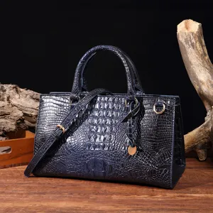 Detalle de bolso azul marino de cuero con relieve de cocodrilo sobre base madera