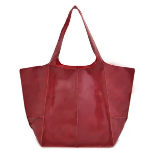 Detalle de la textura de cuero encerado rojo vintage en un bolso tote de gran capacidad.