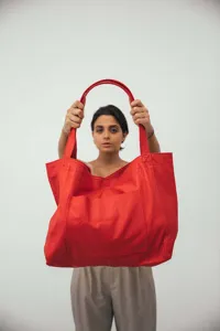 Detalle de un bolso tote grande de cuero rojo suave con bolsillo delantero para mujer