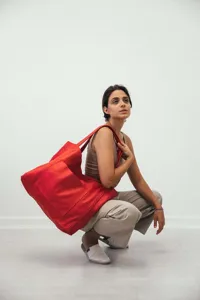 Mujer a la moda con ropa neutra llevando un bolso tote de cuero rojo vibrante y grande