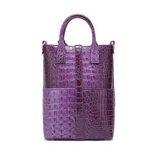 Detalle de bolso de mano morado vintage con relieve de cocodrilo y asas resistentes.