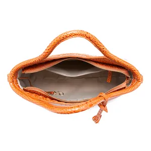 Vista superior de bolso naranja con grabado de cocodrilo y bolsillos internos.