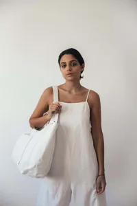 Mujer con mono blanco que lleva un bolso tote grande de cuero blanco roto