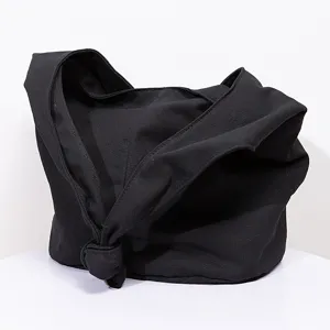 Detalle de un bolso tote retro de lona negra con un diseño único de correa con nudo