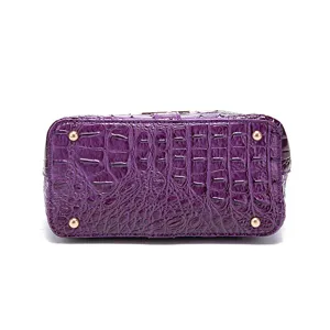 Vista inferior del bolso morado con grabado de cocodrilo y pies protectores dorados