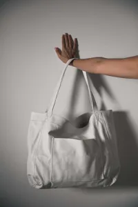 Bolso tote grande minimalista de cuero encerado blanco con bolsillo frontal en la mano