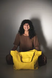 Bolso tote de cuero suave amarillo con bolsillo frontal mostrado en entorno de estilo