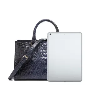 Bolso de mano azul oscuro con textura de cocodrilo junto a tableta para comparar
