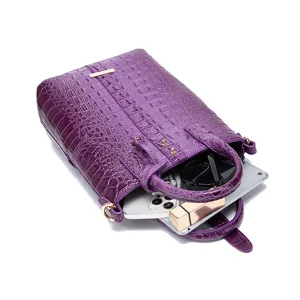 Vista detallada de la gran capacidad del bolso morado con estampado de cocodrilo y objetos