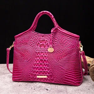 Detalle del bolso de mano fucsia con relieve de cocodrilo y herrajes dorados