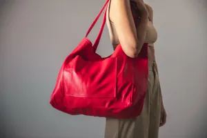 Vista detallada de un gran bolso tote de cuero encerado rojo con un práctico bolsillo exterior