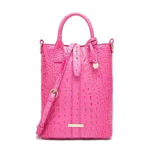 Vista detallada de un bolso rosa con textura de cocodrilo y correa para el hombro