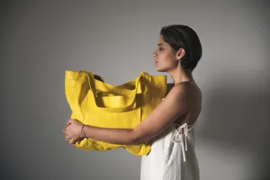 Vista lateral de mujer con bolso tote grande de cuero amarillo mostrando textura suave