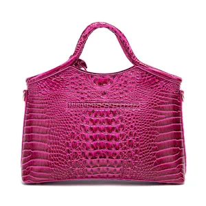 Vista detallada de un bolso fucsia con textura de cocodrilo en relieve.
