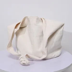 Primer plano de un bolso de hombro de lona crema minimalista con detalle de nudo único