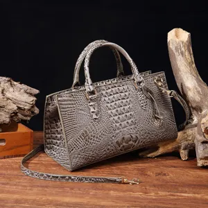 Primer plano detallado de bolso gris con grabado de cocodrilo sobre madera rústica