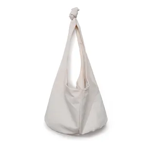 Detalle de bolso de hombro en lona blanco crema con diseño de correa anudada única.