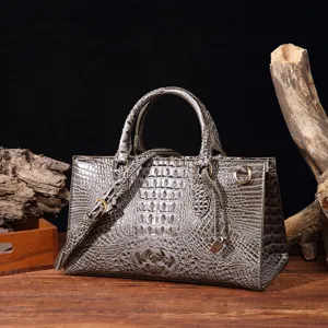 Detalle de bolso gris con grabado de cocodrilo y acentos de madera de estilo vintage.