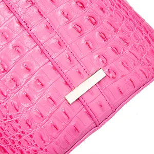 Detalle de textura de piel de cocodrilo rosa brillante en un bolso