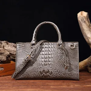 Primer plano de bolso gris con grabado de cocodrilo y elegantes herrajes dorados