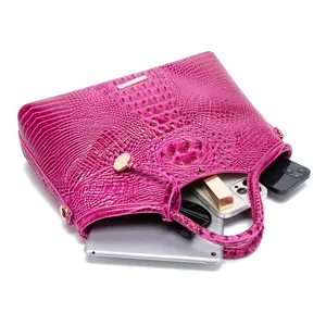 Detalle de bolso fucsia con grabado de cocodrilo mostrando espacio para tableta y móviles.