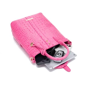 Vista detallada del interior de un bolso rosa con patrón de cocodrilo y capacidad
