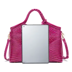 Bolso de mano magenta con relieve de cocodrilo mostrado con tablet para referencia de tamaño