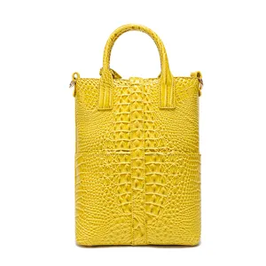 Vista frontal de un bolso amarillo vintage con relieve de cocodrilo y asas superiores