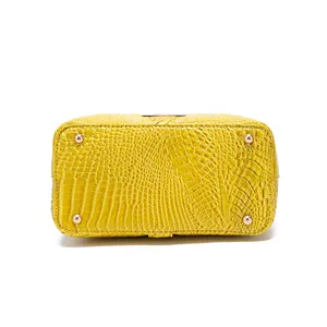 Vista inferior detallada de un bolso amarillo de cocodrilo con pies metálicos