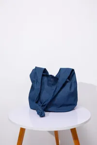 Vista detallada de un bolso tote de mezclilla azul con una original correa de nudo