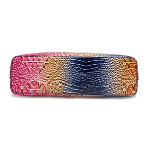 Vista inferior de un bolso multicolor con relieve de cocodrilo y pies protectores dorados.