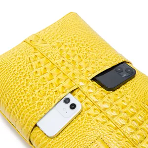 Primer plano de bolso amarillo con relieve de cocodrilo y bolsillos para móviles